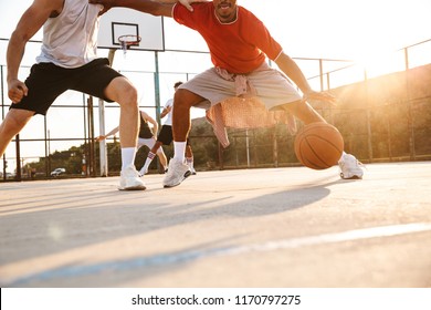 Cropped image of young multiethnic men basketball players playing basketball at the sport ground