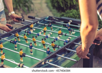 Cropped image of young people playing foosball while resting outdoors
