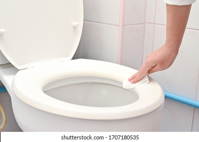 Cropped image of  young woman cleaning Toilet seat by a wet wipe in public restroom.