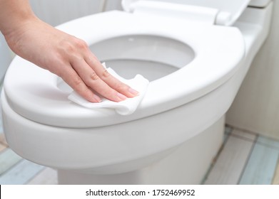 Cropped Image Of Young Woman Cleaning Toilet Seat By A Wet Wipe In Public Restroom