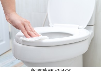 Cropped Image Of Young Woman Cleaning Toilet Seat By A Wet Wipe In Public Restroom