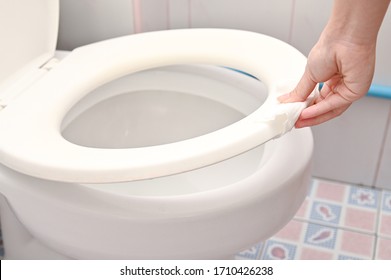 Cropped Image Of  Young Woman Holding Toilet Seat Cover By A Wet Wipe In Public Restroom.