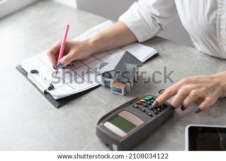 Cropped image of a young woman holding a house model over the comfortable office desk