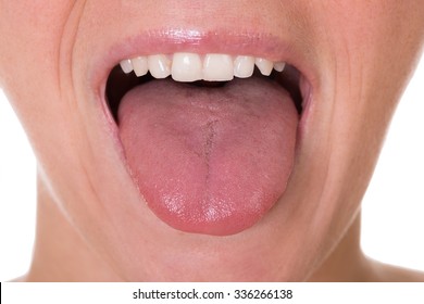 Cropped image of young woman showing tongue over white background