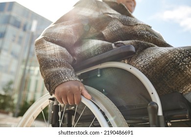 Cropped Low Angle Shot Of Black Woman In Wheelchair Pushing Wheels In Sunlight Outdoors, Copy Space