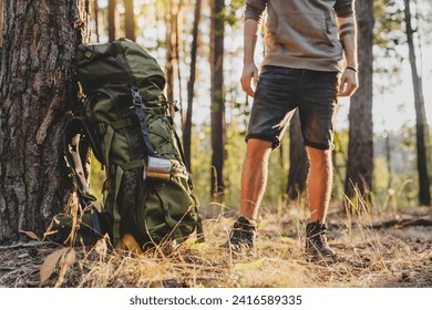 Cropped of male hiker standing near his camping backpack in forest. Away from everything concept. Adventurer explorer traveler in woods in summer - Powered by Shutterstock