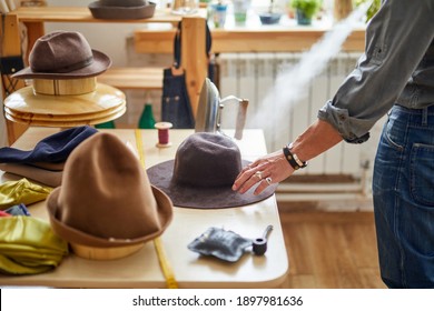 cropped male tailor steaming the hat for sale, the final sewing action. close-up photo on desktop with tools and hats - Powered by Shutterstock