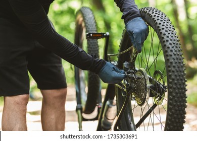 Cropped Of Man Cyclist Repairing Broken Bike Chain Over Green Background