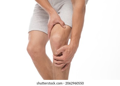 Cropped millennial european male athlete suffering from knee pain, presses his hand to sore spot, isolated on white background, free space. Arthritis, trauma, health problem and injury, close up