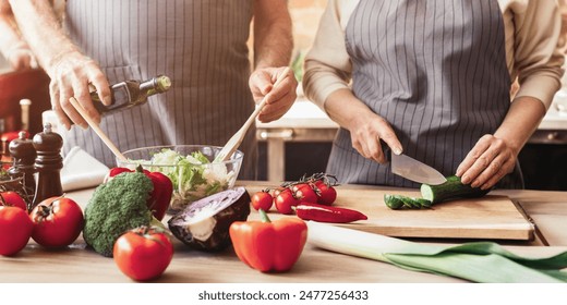 Cropped of older couple happily prepares a meal together in their kitchen. The woman is stirring a salad in a bowl while the man holds a red pepper. - Powered by Shutterstock