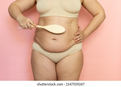 Cropped overweight woman belly in lingerie, excessive weight, visceral fat abdomen. Brush dry massage with natural stubble, rubbing. Hands on waist. Loss weight. Anticellulite procedures at home