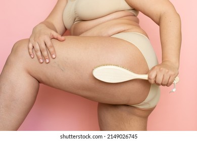 Cropped overweight woman body in lingerie with excessive weight, visceral fat. Applying brush dry massage with natural stubble, rubbing dozed hips. Problem cellulite and varicose veins. Close up