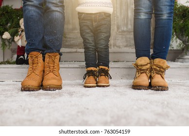Cropped parents little son legs Child boy in sweater yellow boots staying porch snow steps at light house with decorated New Year home. Christmas good mood. Family on holiday 2019. Bottom view mockup.