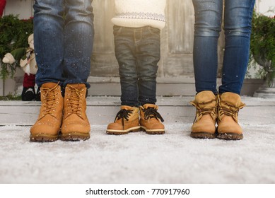 Cropped parents little son legs Child boy in sweater yellow boots staying porch snow steps at light house with decorated New Year home. Christmas good mood. Family on holiday 2019. Bottom view mockup.