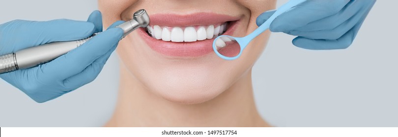 Cropped perfect smile and dentist hands holding a dental drill and an angle mirror. Dentistry and teeth treatment