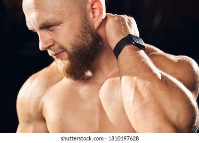 Cropped photo of a bearded male athlete touching his neck looking distressed at the gym - Shutterstock ID 1810197628