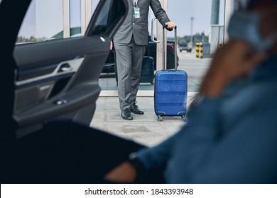 Cropped photo of a Caucasian man in a face mask waiting for his private driver - Powered by Shutterstock