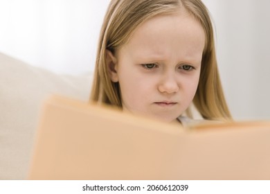 Cropped Photo Of Confused Blond Little Girl Reading A Book.