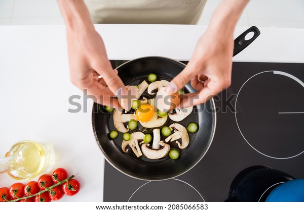 Cropped photo cooking man adding sliced\
vegetables mushrooms on frying pan making\
omelette