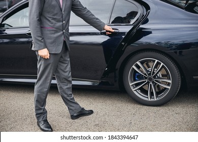Cropped photo of a driver in a stylish suit opening the car door for his passenger - Shutterstock ID 1843394647
