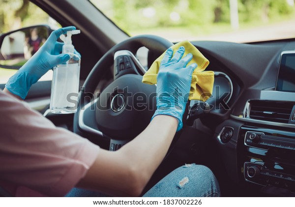 Cropped photo of driving\
teacher girl sit car wash rag disinfect antiseptic bottle steering\
wheel before student come ride learn wear blue latex gloves in city\
center