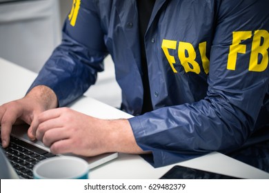 Обрезанное фото агента ФБР, использующего ноутбук в офисе