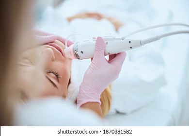 Cropped photo of a female dermatologist treating her patient with the fractional radio frequency microneedle machine