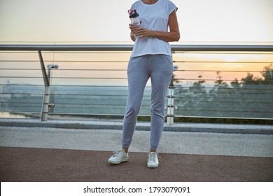 Cropped photo of a fit woman holding a plastic bottle of water in her hand