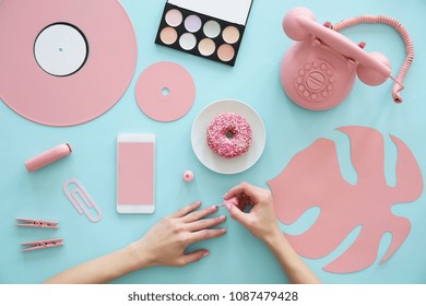 Cropped Photo Of A Girl Painting Her Nails On A Blue Table With Pink Items