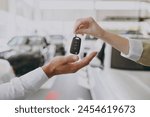 Cropped photo of male customer buyer client receive car keys fob keyless system from salesman choose auto want buy new automobile in showroom vehicle salon dealership store motor show. Sales concept