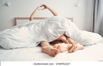 Cropped photo of newly wedded couple making a heart shape with their hands in bed - Shutterstock ID 1744952147
