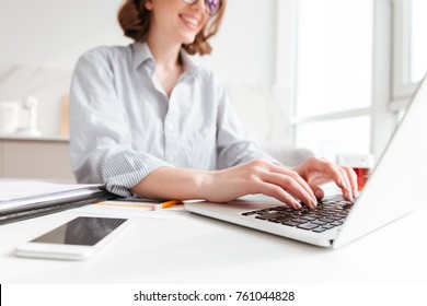 Cropped photo of pretty brunette woman typing email on laptop computer while sitting at home, selective focus on hand - Shutterstock ID 761044828