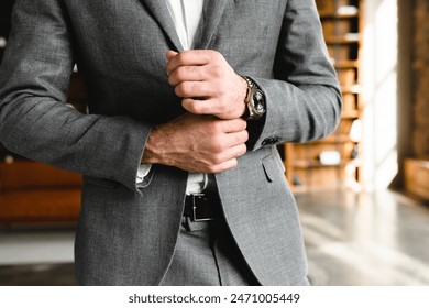 Cropped photo of prosperous businessman touching his sleeves of tuxedo in office. Manager boss millionaire fixing formal suit attire at workplace. Expensive wristwatch - Powered by Shutterstock