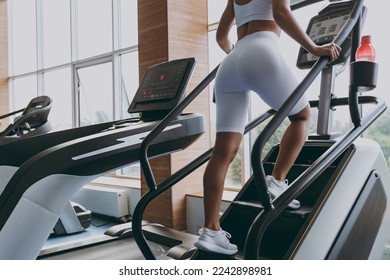 Cropped up photo shot back view young strong skinny sporty athletic sportswoman woman in white sportswear warm up train run on a treadmill climber stairs machine in gym indoor Workout sport concept - Shutterstock ID 2242898981
