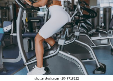 Cropped Up Photo Shot Young Strong Sporty Athletic Sportswoman Woman 20s In White Sportswear Earphones Listen Music Warm Up Training Use Exercise Bike In Gym Indoor Workout Sport Motivation Concept