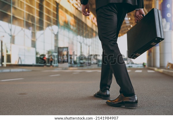 Cropped up photo shot young traveler businessman\
man wearing black dinner suit walk go outside at international\
airport terminal with attache case People air flight business trip\
lifestyle concept.
