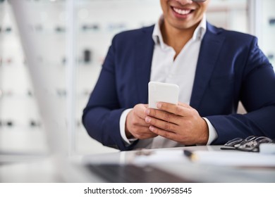 Cropped Photo Of A Smiling Male Client With His Smartphone Sitting At The Optician Office