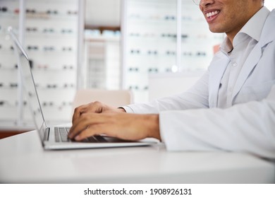 Cropped Photo Of A Smiling Male Optician In A Lab Coat Working On His Computer