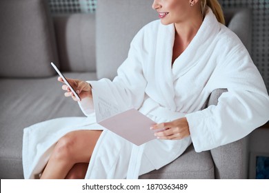 Cropped photo of a smiling woman with the salon service menu sitting on the sofa - Powered by Shutterstock