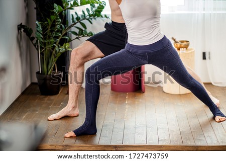 cropped photo of strong flexible man teach his girlfriend to take the right position in yoga, couple do exercises at home, wearing sportswear. isolated in light room