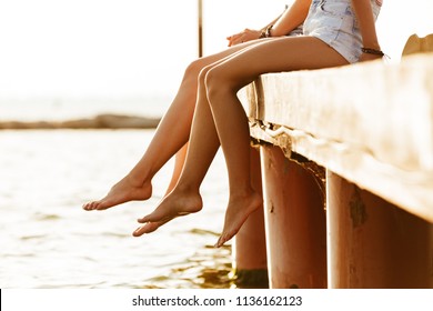 Cropped Photo Of Two Friends Women Sitting Outdoors On The Beach.