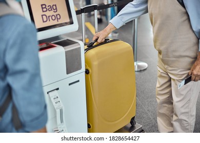 Cropped Photo Of Two Passengers Printing Out A Baggage Label At An Airport Self-service Kiosk