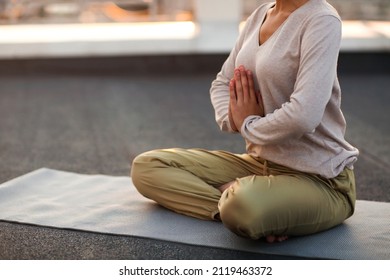 Das gepflanzte Foto von unerkennbarer Frau, die in Lotus sitzt, posiert auf Matte und übt Yoga, Weibchen, die Namensgeste tun, während sie im Freien meditieren. Konzept der Meditation und Achtsamkeit