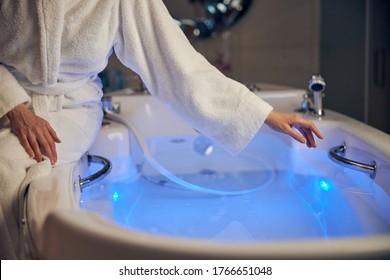 Cropped Photo Of A Woman In A Bathrobe Reaching For A Grab Bar In The Bathtub