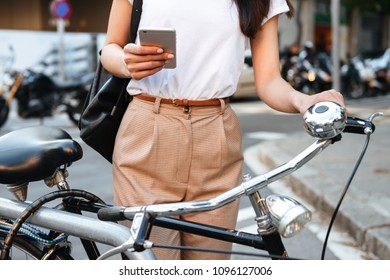 Cropped photo of woman walking outdoors on bicycle using mobile phone. - Shutterstock ID 1096127006