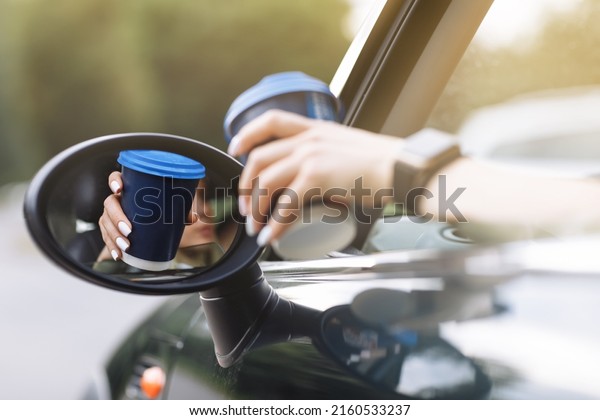 cropped photo of woman\'s hand holding blue paper\
cup of coffee in car. Hot drink take away. Travel with coffee.\
Concept of coffee with you.\
Mockup.