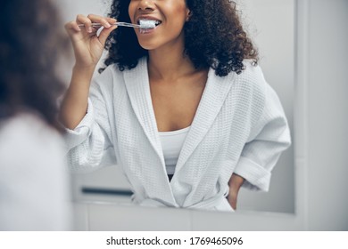 Cropped photo of a young African American lady standing in front of the bathroom mirror - Powered by Shutterstock