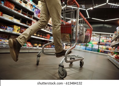 Cropped Photo Of Young Man In Supermarket Choosing Products With Shopping Trolley And Have Fun Riding