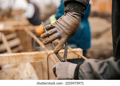 Cropped picture of a builder's hands working with pliers and making foundation on site. - Shutterstock ID 2255973971