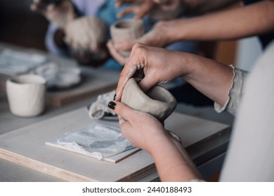 Cropped picture of female pottery class student's hands making earthenware at ceramics studio. Close up of pottery course attendee leaning clay work, handcrafts and earthenware making at workshop. - Powered by Shutterstock